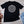 Drink Package Club cruise T-shirt with white circular badge lettering, stars, gold anchors, and colourful cocktail graphics.